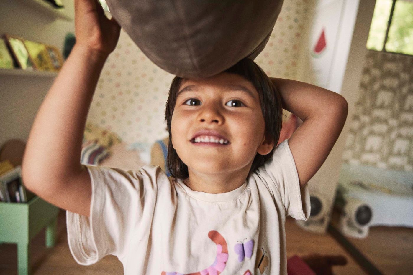 A smiling child in a white t-shirt balancing a toy on their head.