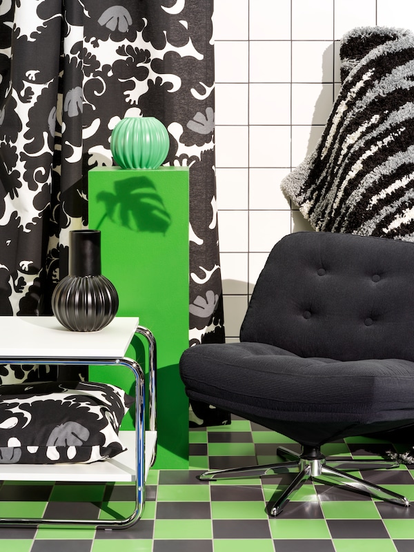 A black DYVLINGE swivel armchair is surrounded by home furnishing from the latest Nytillverkad release.