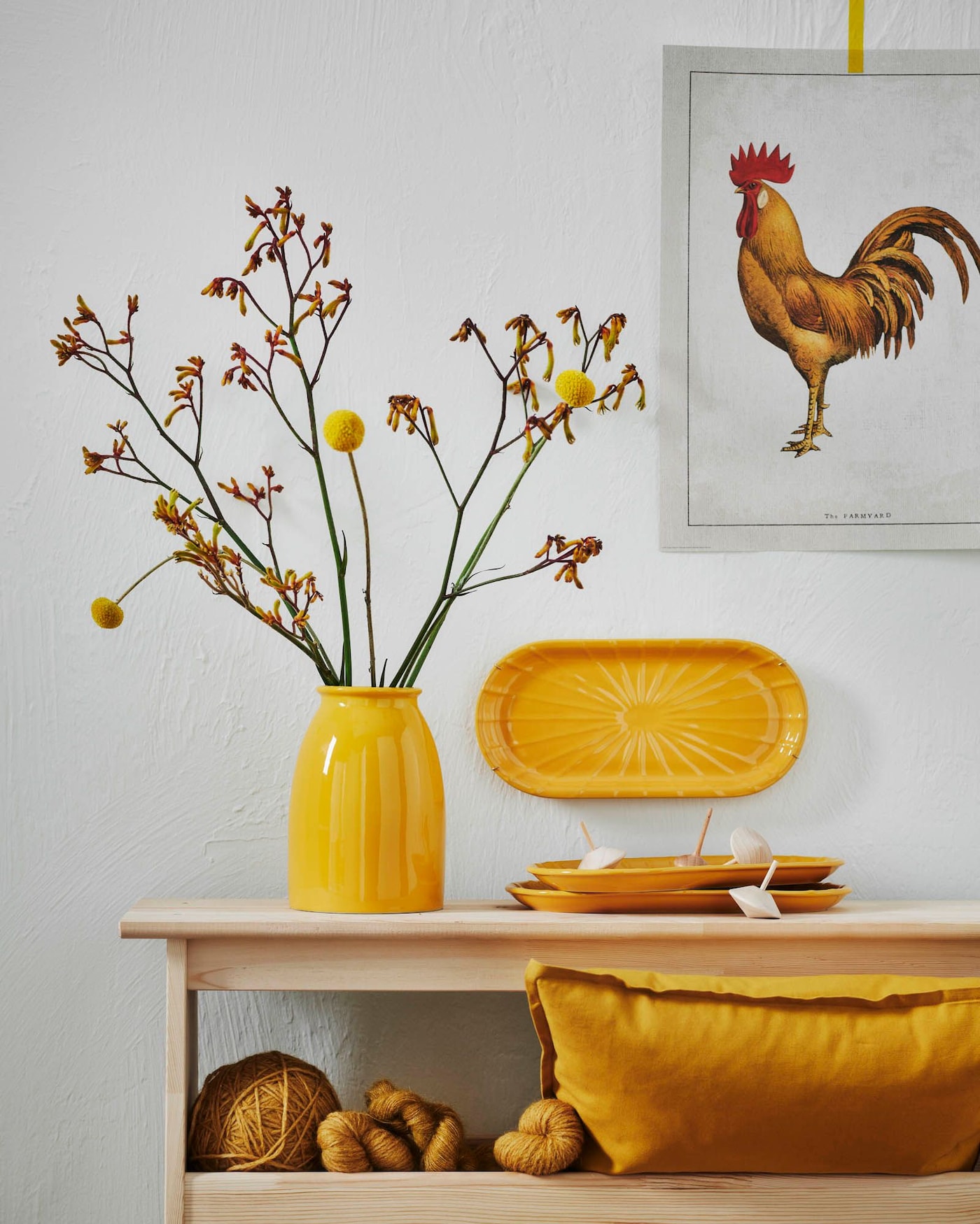 A wooden bench with storage, styled with ceramics, balls of yarn and a cushion – all in vibrant yellow.