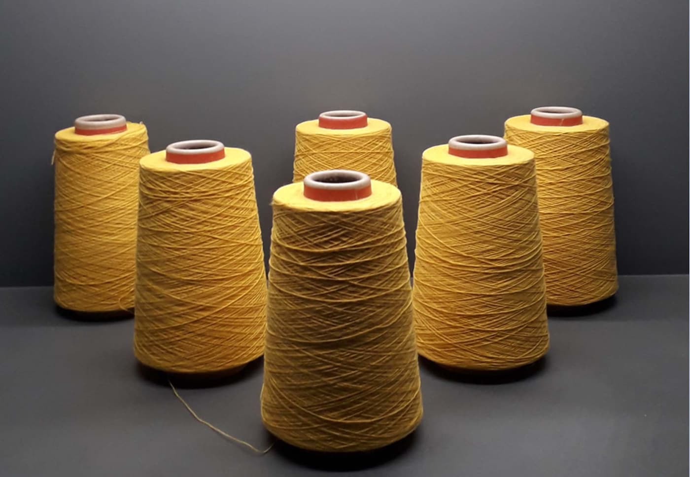 Six large spools of fine yellow yarn.